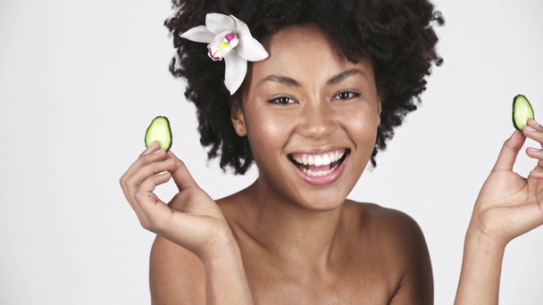 happy naked african american girl holding slices of cucumber, laughing and covering eyes on white  - Footage, Video