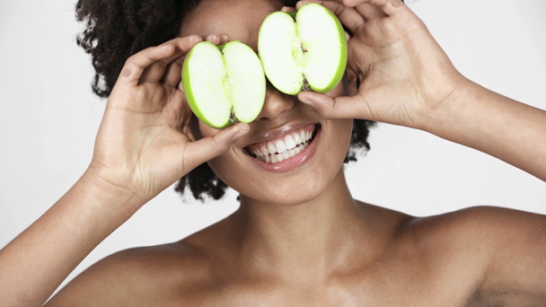 alegre desnudo afroamericano chica mirando mitades de manzana, cubriendo los ojos y riendo en blanco
  - Metraje, vídeo