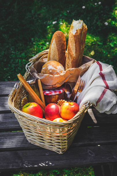 Picnic basket filled with fruit , bread and jar with apricot jam - Foto, imagen