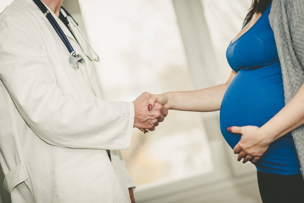 рукостискання між вагітною жінкою і лікарем
 - Фото, зображення
