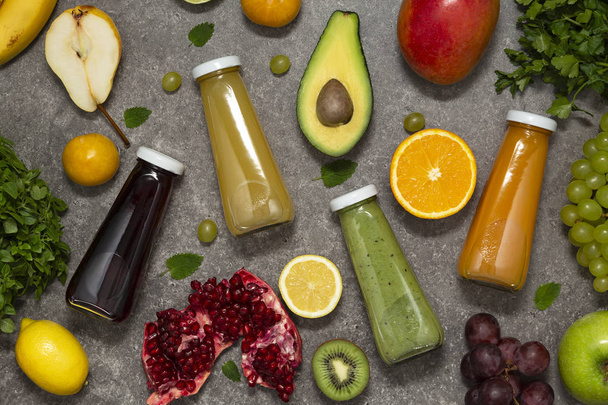 Colorful smoothies in bottles with fresh tropical fruit and vegetables on concrete background, top view. Flat lay.  Healthy, clean eating, vegan, vegetarian, detox, dieting food concept. - Zdjęcie, obraz