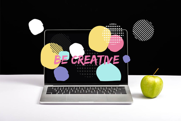 fresh green apple and laptop on table with be creative lettering on screen and abstract circles around on black - Photo, Image