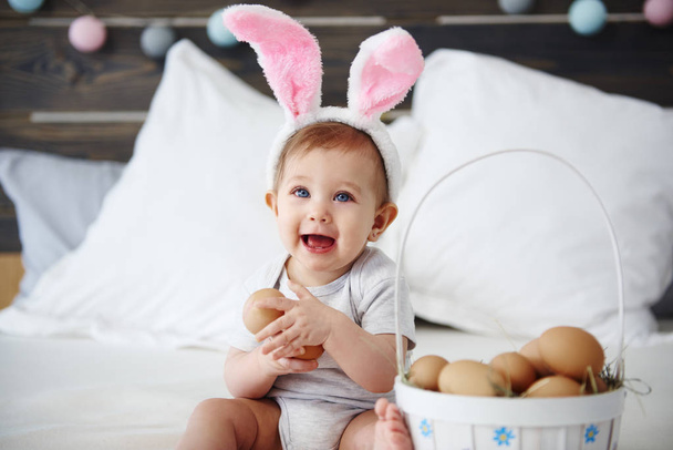 Retrato de bebé con orejas de conejo sosteniendo huevos
  - Foto, imagen