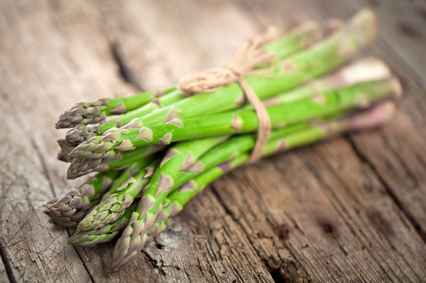close-up view of fresh healthy tied asparagus on wooden table - Valokuva, kuva