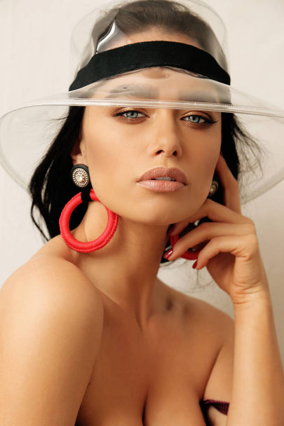 beautiful woman with dark hair in fashion transparent hat and lu - Foto, imagen