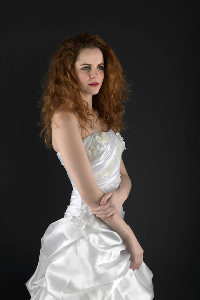 beautiful young woman with long hair in a white dress on a black background - 写真・画像