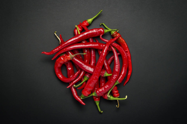 Red hot chili paprika egy kör alakú, fekete háttér előtt sorakoznak. Lapos feküdt, top view - Fotó, kép