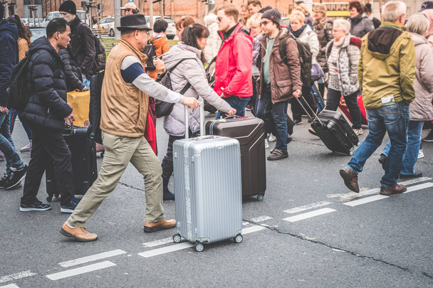 Путешествующие люди с багажом пересечения улицы возле железнодорожного вокзала - Фото, изображение
