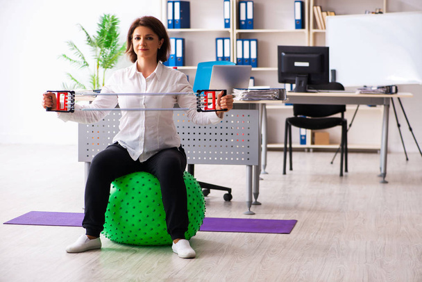 Employée d'âge moyen faisant des exercices au bureau
  - Photo, image
