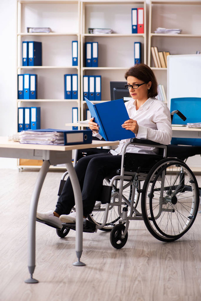 Vrouwelijke werknemer in rolstoel op kantoor   - Foto, afbeelding