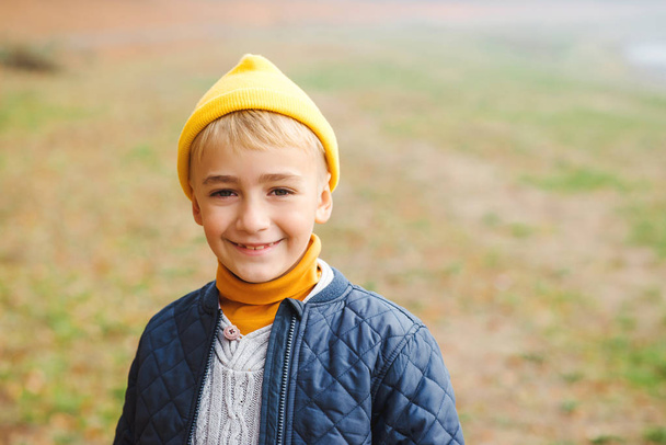 Портрет щасливого хлопчика на фоні природи. Стильний хлопчик в жовтому капелюсі сміється і дивиться на камеру
.  - Фото, зображення