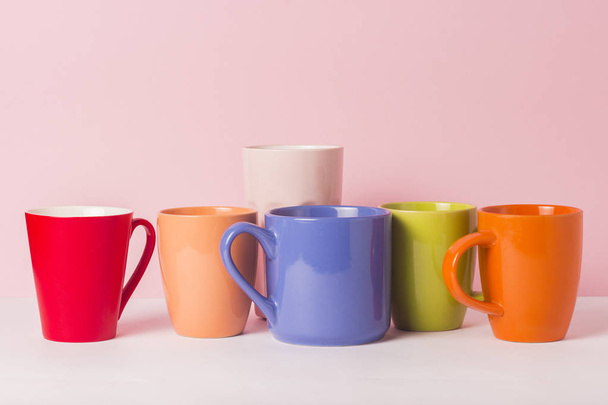 ピンクの背景でコーヒーまたは紅茶の色とりどりのカップがたくさん。フレンドリーな会社、大家族、紅茶やコーヒーのカップのための会合の友人の概念. - 写真・画像