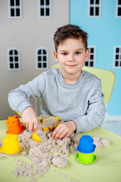 Happy boy plays kinetic sand at home - Photo, Image