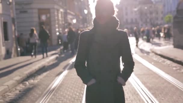 Outdoor portrait of young beautiful fashionable brunette woman walking on the street at autumn. Model wearing stylish gray coat, skinny jeans and black golf. - Video