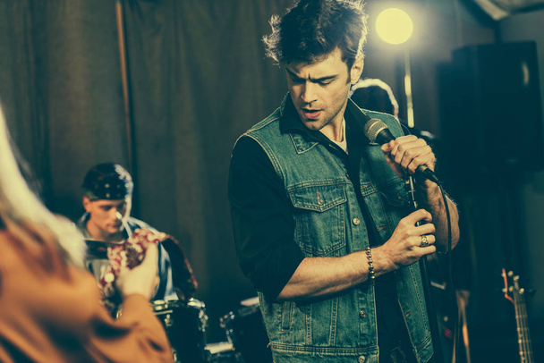 selective focus of handsome singer standing with microphone near rock band - Φωτογραφία, εικόνα
