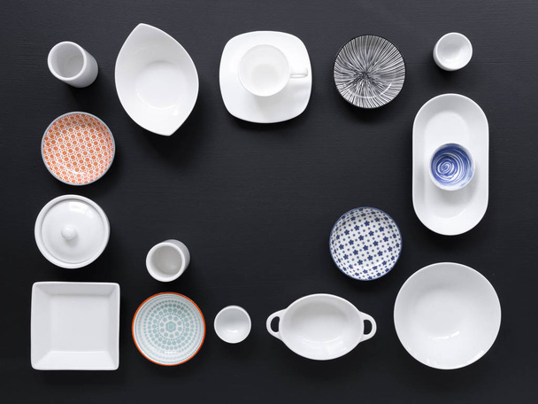 collection of white and colored tableware on black background  - Photo, image