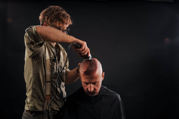 le coiffeur se rase la tête chauve vieil homme dans le studio
 - Photo, image