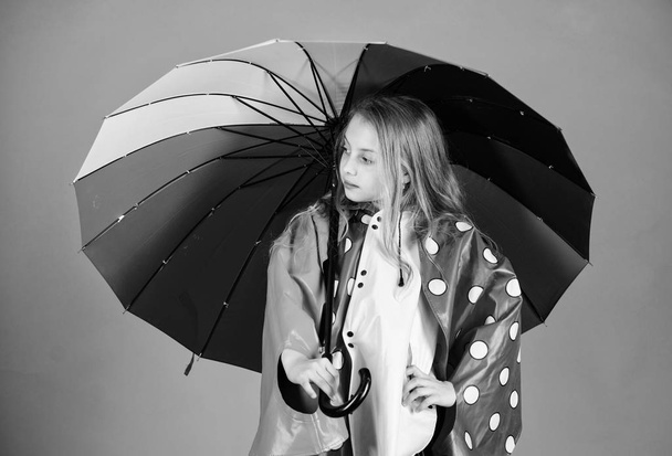 Waterproof accessories for children. Waterproof accessories make rainy day cheerful and pleasant. Kid girl happy hold colorful umbrella wear waterproof cloak. Enjoy rainy weather with proper garments - Foto, Imagem