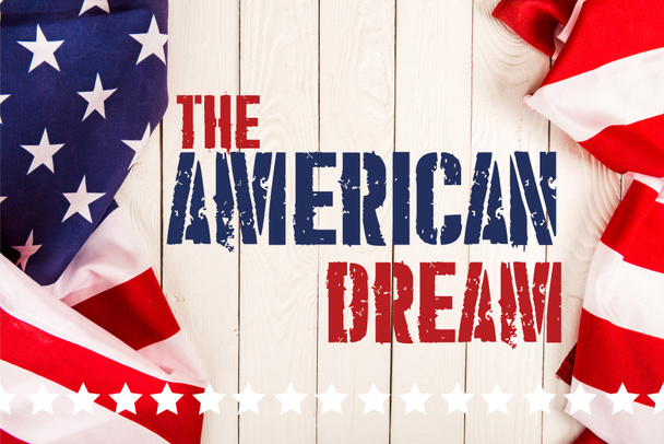 Draufsicht auf amerikanische Flaggen und den amerikanischen Traum-Schriftzug auf weißer Holzoberfläche - Foto, Bild