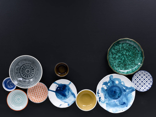 collection of white and colored tableware on black background  - Foto, immagini
