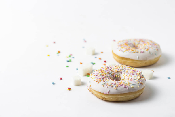 frische leckere Donuts und süße bunte Deko-Bonbons auf weißem Hintergrund. Bäckereikonzept, frisches Gebäck, leckeres Frühstück. - Foto, Bild