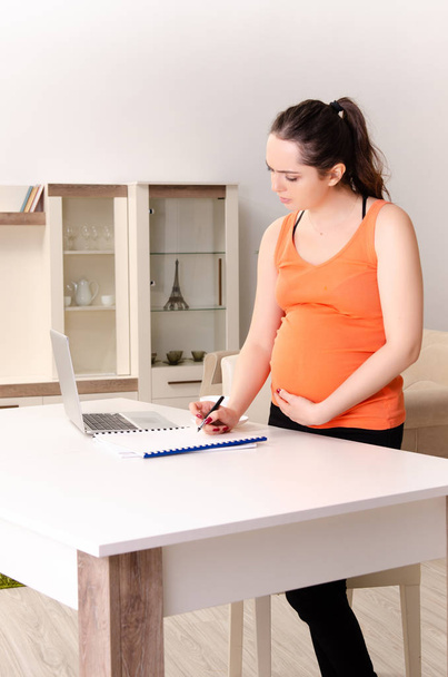 Mujer embarazada joven que trabaja en casa
  - Foto, imagen