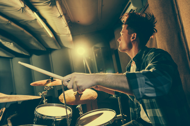 handsome musician holding drum sticks and playing drums - Photo, Image