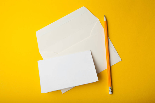 leere Vorlagenkarte und Umschlag mit Bleistift auf gelbem Rücken - Foto, Bild