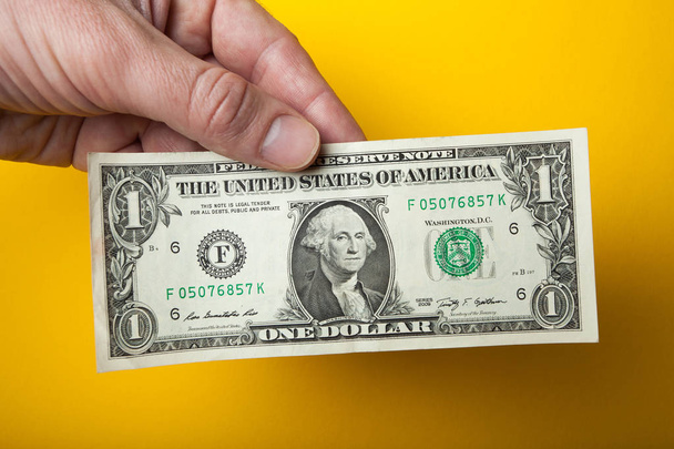 Sale, one dollar in hand on a yellow background. - 写真・画像