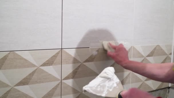 Worker with a rubber spatula fill the seams with a solution. Finishing works, focus on hands. The technology of laying tile. - Footage, Video