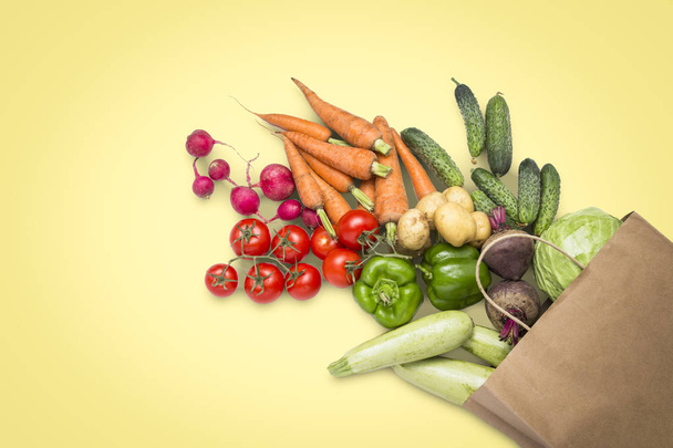 Бумажный пакет и свежие органические овощи на светло-желтом фоне. Концепция закупки сельскохозяйственных овощей, заботы о здоровье, вегетарианстве. Деревенский стиль, ярмарка ферм. Плоский, вид сверху
 - Фото, изображение