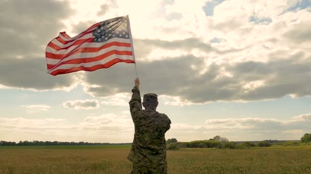 Soldado fique no campo e segure a bandeira americana contra o céu da noite. Movimento lento
 - Filmagem, Vídeo