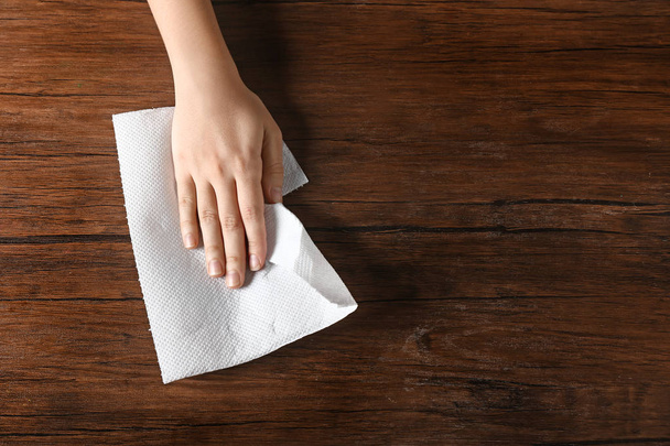 Woman wiping wooden table with paper towel - Foto, imagen