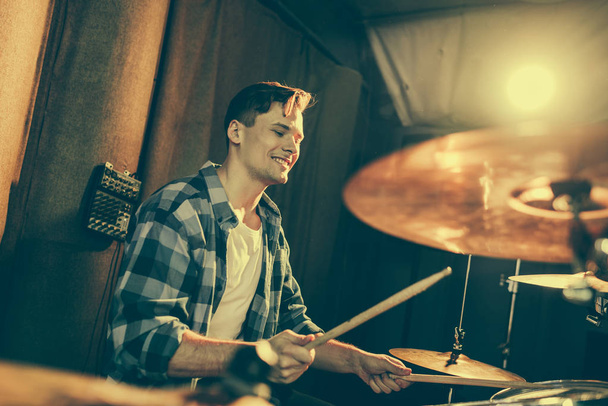 selective focus of handsome drummer holding drum sticks and playing drums  - Foto, Imagem