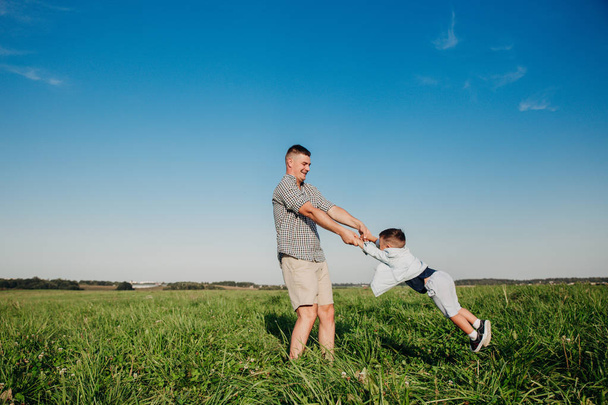Χαρούμενος μπαμπάς παίζει με το παιδί του στο πεδίο - Φωτογραφία, εικόνα