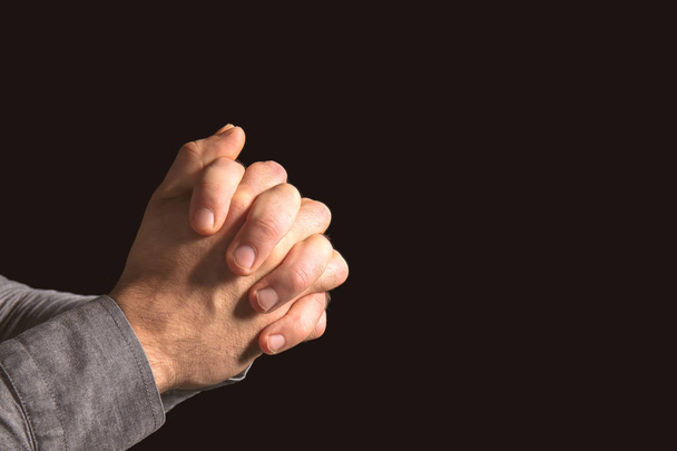 Руки релігійного чоловіка моляться на чорному тлі
 - Фото, зображення