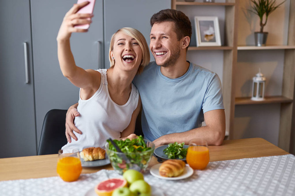 Laughing couple taking selfie during breakfast - Фото, зображення