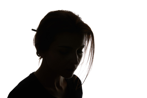 Silhouette einer nachdenklichen Frau, die isoliert auf Weiß herabblickt - Foto, Bild
