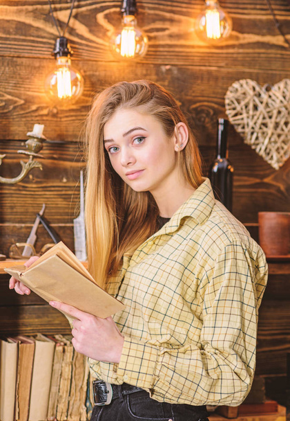 Poetry evening concept. Girl in casual outfit in wooden vintage interior enjoy poetry. Girl reading poetry in warm atmosphere. Lady on dreamy face in plaid clothes holds book, reading poetry - Valokuva, kuva