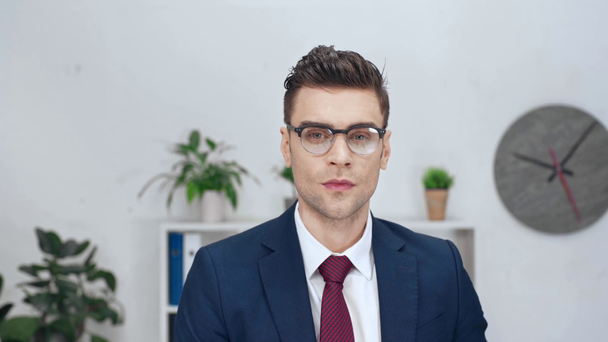 handsome businessman looking at camera, smiling and touching eyeglasses - Materiał filmowy, wideo