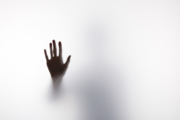 Blurry silhouette of person touching glass with hand - Foto, Bild