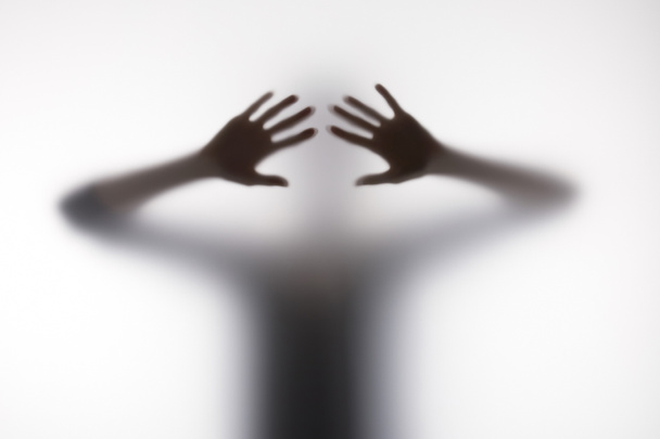 Blurry silhouette of person touching glass with hands - Foto, immagini