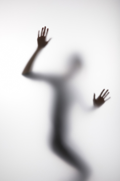 Blurry silhouette of person touching glass with hands - Fotó, kép