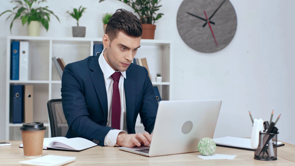 figyelmes üzletember használ laptop, míg ült munkahelyi irodájában - Felvétel, videó