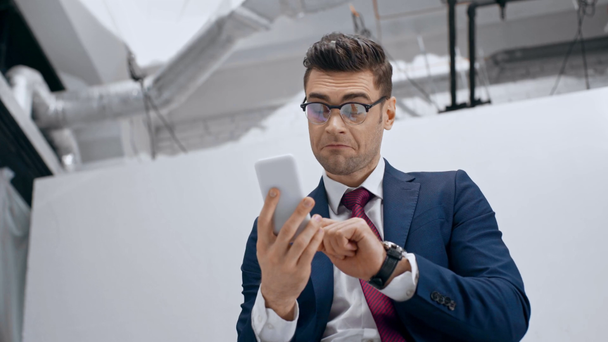 jóképű üzletember, mosolyogva, és megható nyakkendő, miközben selfie smartphone - Felvétel, videó