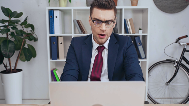 elégedetlen üzletember használ laptop, míg ült munkahelyi irodájában - Felvétel, videó