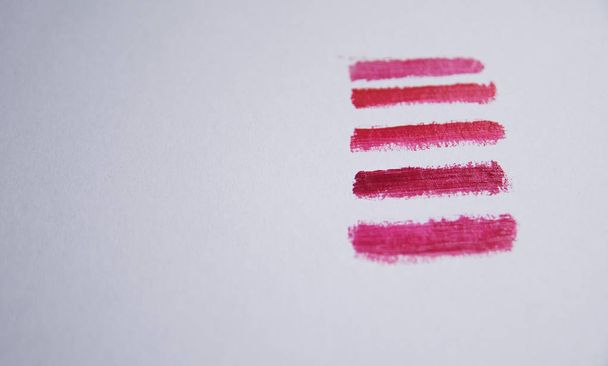 cosmetic samples of five red shades of lipstick on white paper on the right side - Fotó, kép