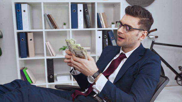 幸せの成功したビジネスマンがオフィスでドル紙幣を数える - 映像、動画
