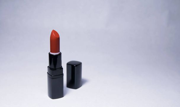 One Carrot-colored Lipstick and black caps stand vertically at a distance from each other on a white background - Fotó, kép