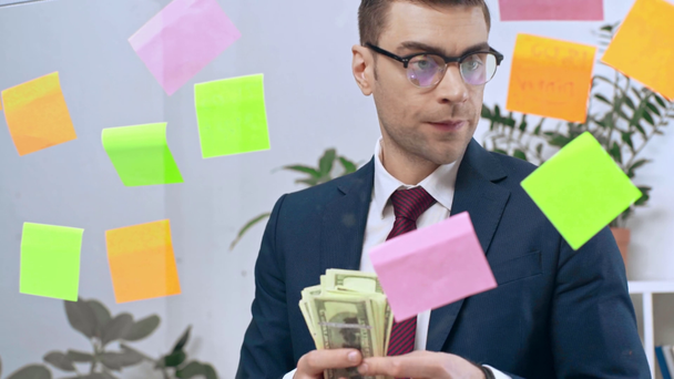 homem de negócios sério contando notas de dólar enquanto olha para notas pegajosas
 - Filmagem, Vídeo